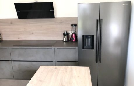 Küchenstudio Eine kleine Küche mit Kühlschrank und Tisch, ausgestattet mit den wichtigsten Geräten.