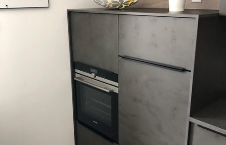 Küchenstudio Eine kleine Küche mit Backofen und Kühlschrank für Referenzen.