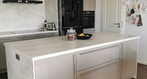 Küchenstudio Referenzen: Eine moderne Küche mit einer weißen Insel und Holzböden.