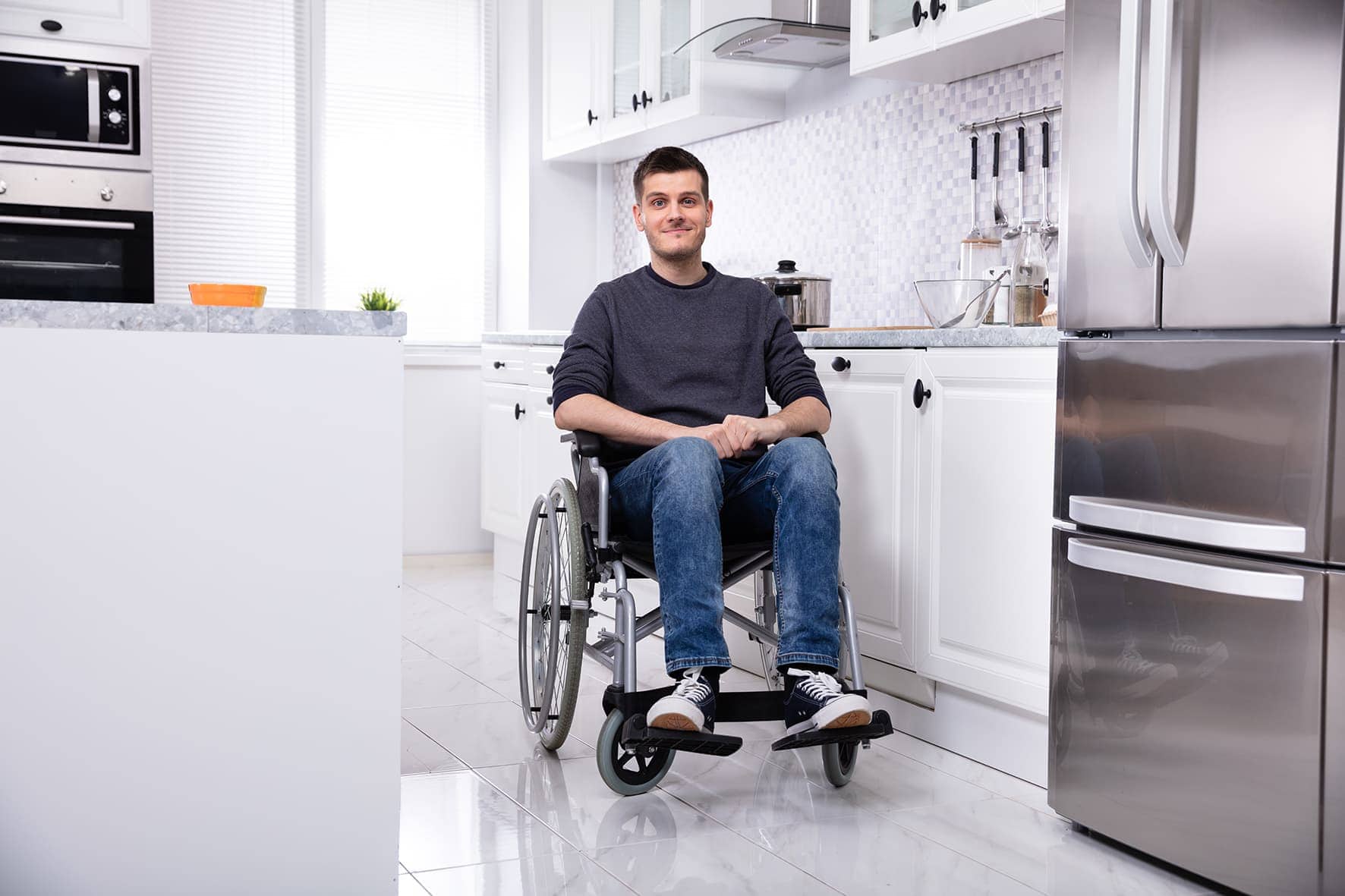 Küchenstudio Ein junger Mann im Rollstuhl sitzt in einer Küche.