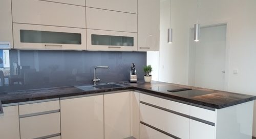 Küchenstudio Eine Küche mit weißen Schränken und Arbeitsplatten und tadellosen Referenzen.