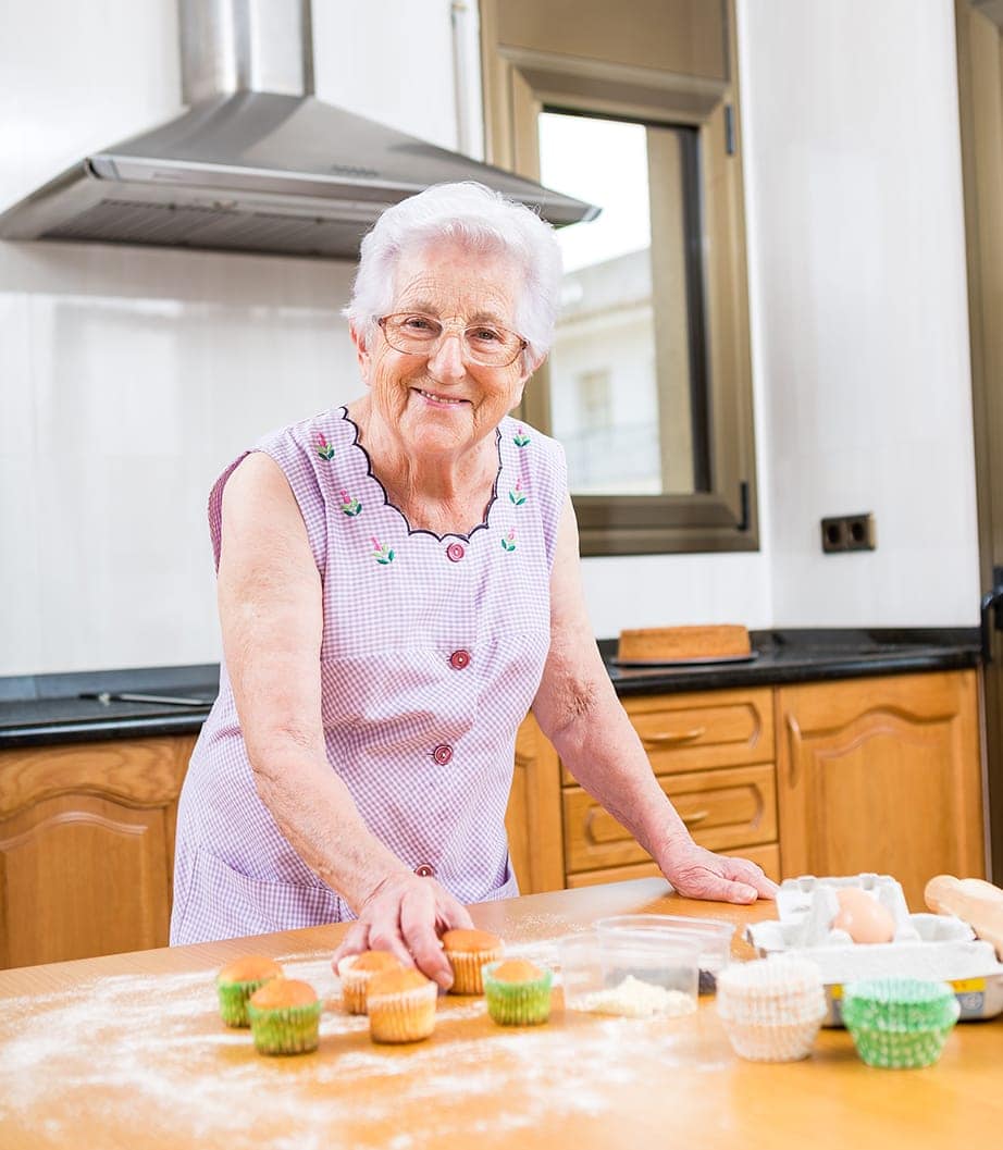 Küchenstudio Eine ältere Frau backt Cupcakes in der Küche.