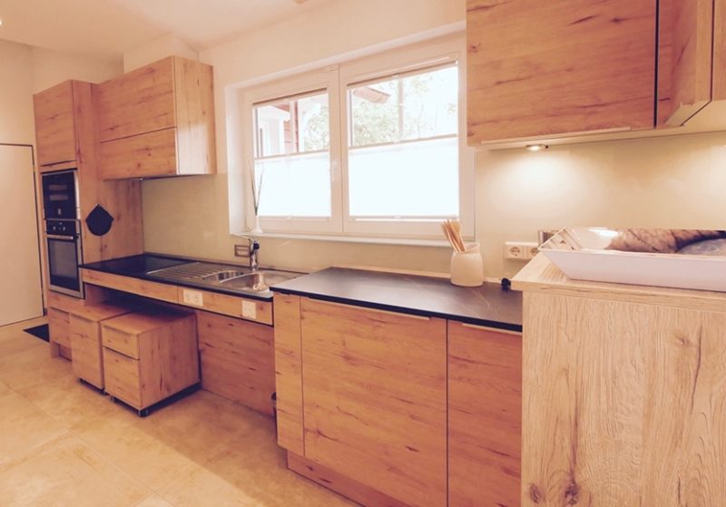 Küchenstudio Eine Küche mit Holzschränken und einem Waschbecken.