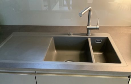 Küchenstudio Eine Küchenspüle mit grauer Arbeitsplatte.