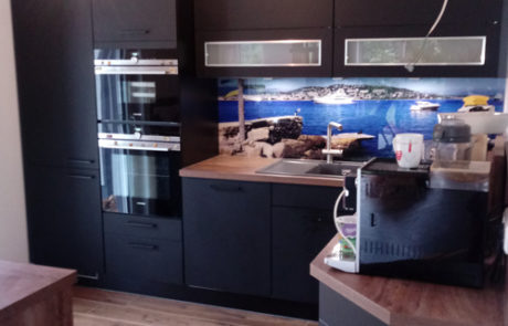 Küchenstudio Referenzen: Eine Küche mit schwarzen Schränken und Holzboden, die als stilvolle Referenz für moderne Innenarchitektur dient.