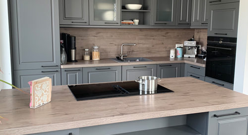 Küchenstudio Eine Küche mit grauen Schränken und einer Arbeitsplatte aus Holz.