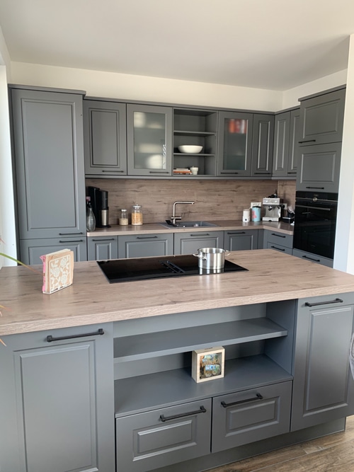 Küchenstudio Eine Küche mit grauen Schränken und einer Arbeitsplatte aus Holz.