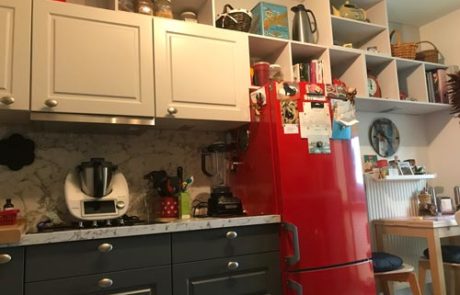 Küchenstudio Eine Küche mit rotem Kühlschrank und weißen Schränken.