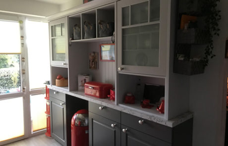 Küchenstudio Eine Küche mit grauen Schränken und einem roten Feuerlöscher.