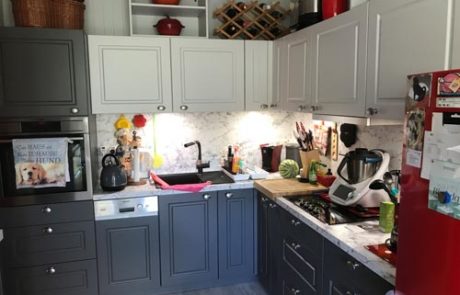 Küchenstudio Eine Küche mit grauen Schränken und einem roten Kühlschrank.