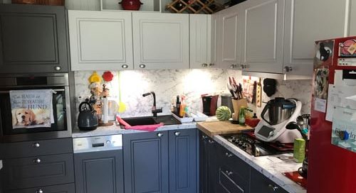 Küchenstudio Eine Küche mit grauen Schränken und einem roten Kühlschrank.