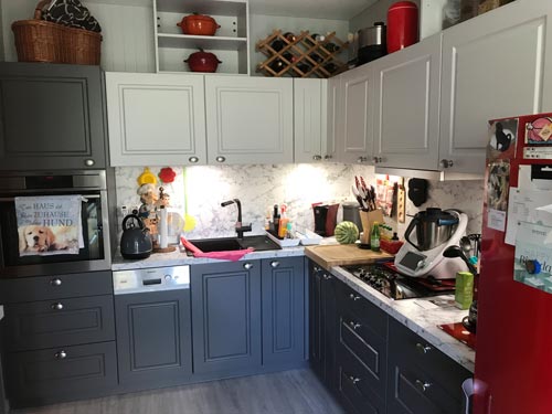 Küchenstudio Eine Küche mit grauen Schränken und einem roten Kühlschrank.