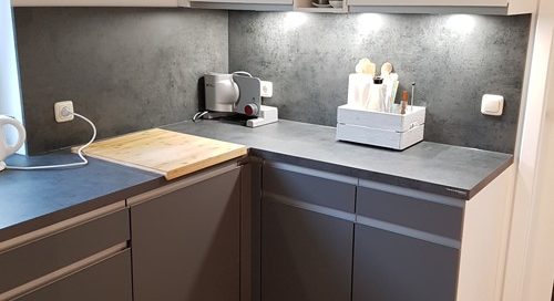 Küchenstudio Eine kleine Küche mit grauen Schränken und einer Spüle, entworfen unter Berücksichtigung von Referenzen.