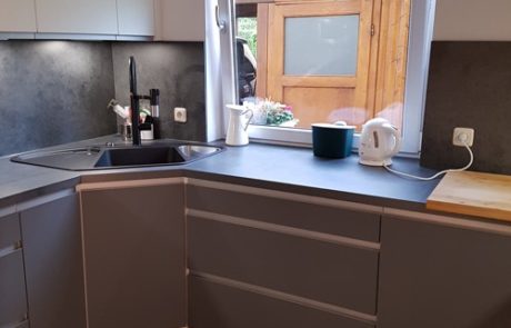Küchenstudio Eine grau-weiße Referenzen-Küche mit Spüle und Fenster.