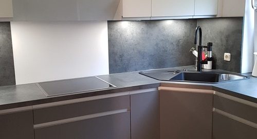 Küchenstudio Eine grau-weiße Küche mit Herd und Spüle, mit stilvollen Referenzen.