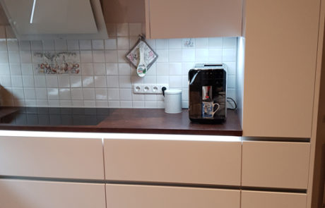 Küchenstudio Eine Küche mit weißen Schränken und einer Kaffeemaschine mit stilvollen Referenzen.