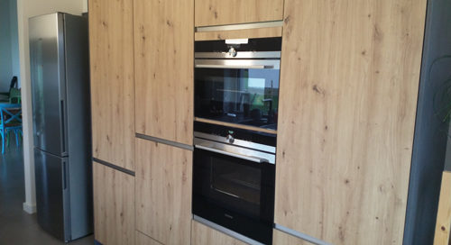 Küchenstudio Referenzen: Eine stilvolle Küche mit Holzschränken und Geräten aus Edelstahl.