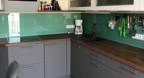 Küchenstudio Eine Küche mit einer grünen Glasrückwand.