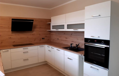 Küchenstudio Eine weiße Küche mit Holzschränken und einer Mikrowelle.