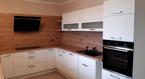 Küchenstudio Eine weiße Küche mit Holzschränken und einer Mikrowelle.