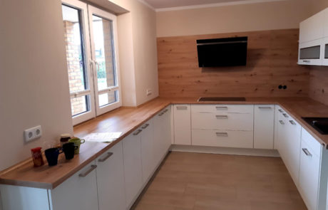 Küchenstudio Eine kleine Küche mit Holzschränken und einem Fernseher.