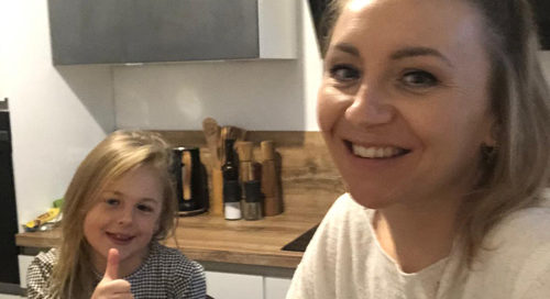 Küchenstudio Eine Frau und ein kleines Mädchen geben in einer Küche den Daumen hoch.