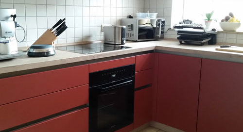 Küchenstudio Eine Küche mit roten Schränken und einem Herd.