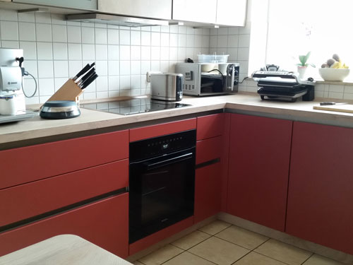 Küchenstudio Eine Küche mit roten Schränken und einem Herd.