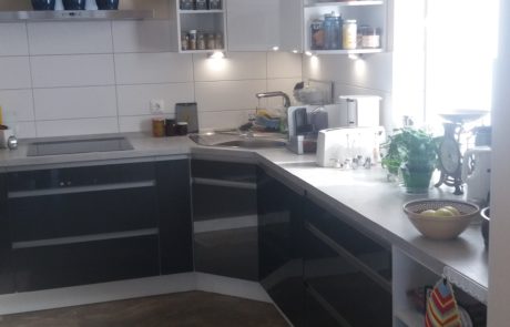 Küchenstudio Eine Küche mit weißen Schränken und schwarzen Arbeitsplatten.