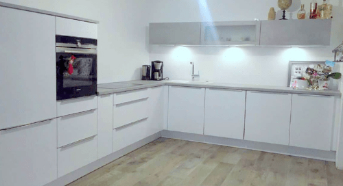 Küchenstudio Eine weiße Küche mit Holzböden und weißen Schränken.