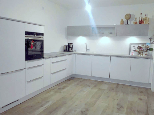 Küchenstudio Eine weiße Küche mit Holzböden und weißen Schränken.