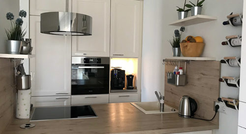 Küchenstudio Eine kleine Küche mit weißen Schränken und einem Herd.