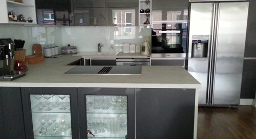 Küchenstudio Eine Küche mit grauen Schränken und Glastüren.