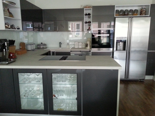 Küchenstudio Eine Küche mit grauen Schränken und Glastüren.