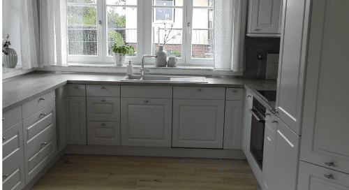 Küchenstudio Eine Küche mit weißen Schränken und einem Fenster.