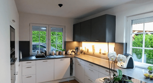 Küchenstudio Ein Bild einer Küche mit weißen Schränken und schwarzen Arbeitsplatten.