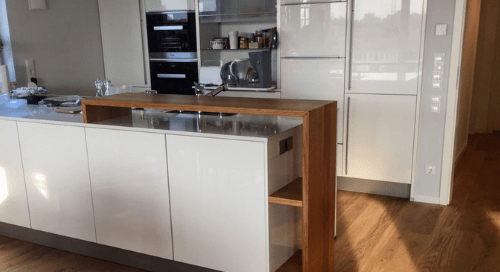 Küchenstudio Eine Küche mit weißen Schränken und Holzböden.