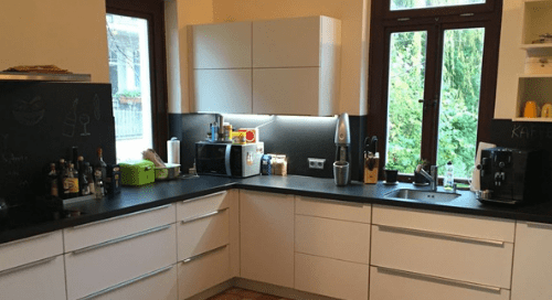 Küchenstudio Eine Küche mit weißen Schränken und schwarzen Arbeitsplatten.