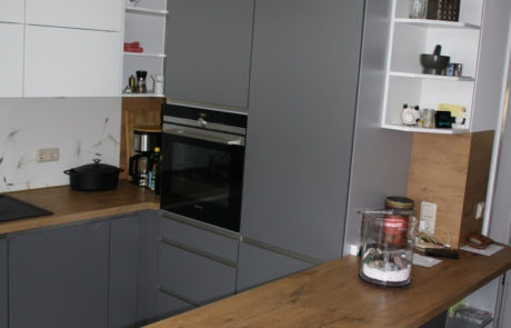 Küchenstudio Eine graue Küche mit einer Arbeitsplatte aus Holz.