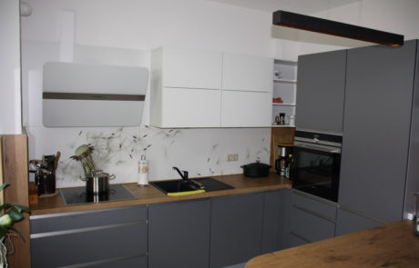 Küchenstudio Eine grau-weiße Küche mit Herd und Spüle.