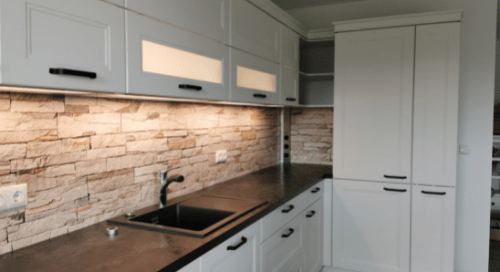 Küchenstudio Eine Küche mit weißen Schränken und schwarzen Arbeitsplatten.