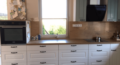 Küchenstudio Eine Küche mit weißen Schränken und einem Fenster.