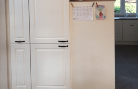 Küchenstudio Eine Küche mit weißen Schränken und einem Kühlschrank.