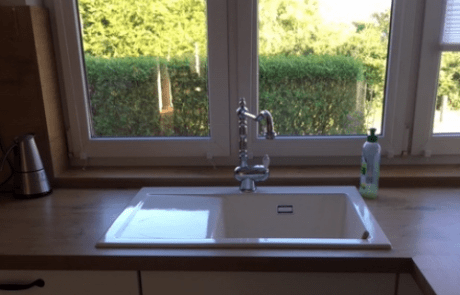 Küchenstudio Ein Waschbecken in einer Küche neben einem Fenster.