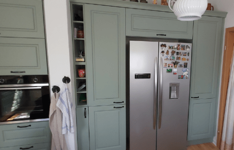 Küchenstudio Eine Küche mit grünen Schränken und einem Kühlschrank.