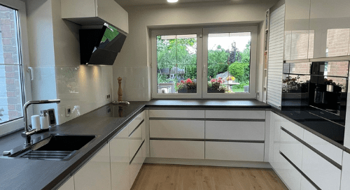 Küchenstudio Eine Küche mit weißen Schränken und schwarzen Arbeitsplatten.