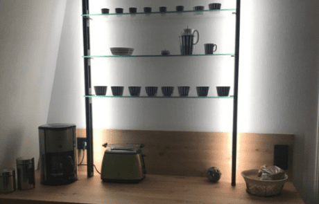 Küchenstudio Ein Regal mit einer Kaffeemaschine und Tassen darauf.