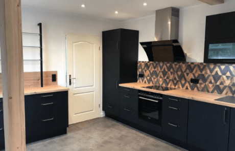Küchenstudio Eine Küche mit schwarzen Schränken und Holzboden.