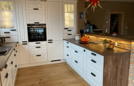 Küchenstudio Eine Küche mit weißen Schränken und Holzboden.