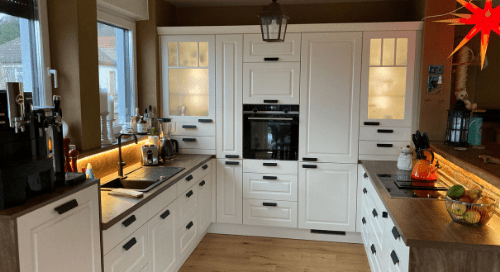 Küchenstudio Eine Küche mit weißen Schränken und Holzboden.